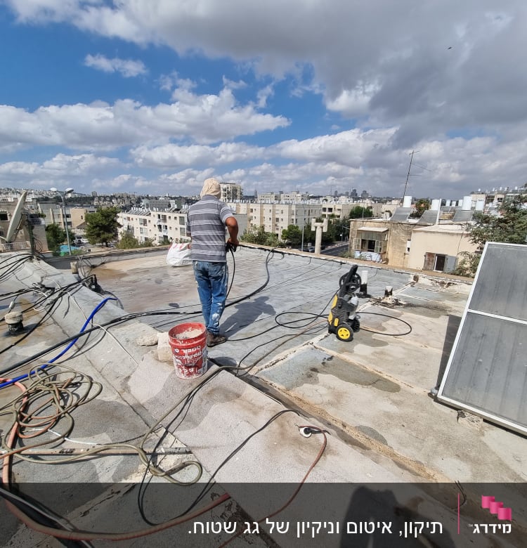 אדם עובד על איטום גג עם צינור מים